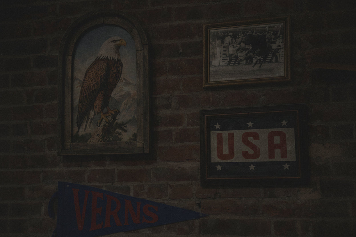Decorative items including a framed picture of an eagle, a framed 'USA' sign, and a blue pennant with 'VERNS' on a brick wall.